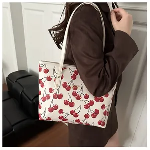Détail d'un sac cabas crème avec imprimés cerises et fines bretelles en cuir souple
