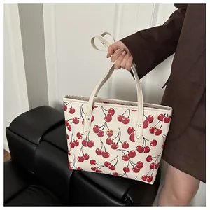 Vue détaillée du sac cabas crème imprimé cerise avec logo doré et deux poignées