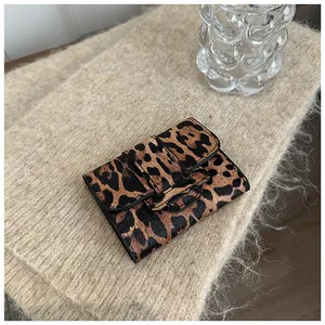 Détail du mini portefeuille léopard sur un tissu tricoté avec verre décoratif