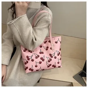 Sac fourre-tout rose à imprimé cerise avec logo doré dans un décor de mode quotidien