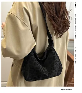 Détail du sac sous le bras noir à motif léopard avec bandoulière réglable porté par un modèle