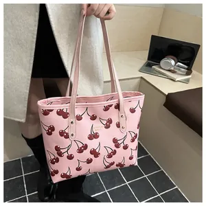 Détail du sac fourre-tout rose à motif cerise avec texte et bandoulière longue