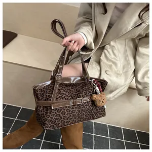 Nahaufnahme der Leoparden-Wildledertasche mit Lederriemen und Plüschbär-Anhänger