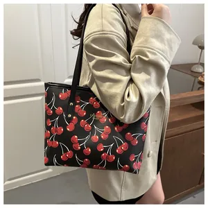 Gros plan d'un sac cabas noir à imprimé cerise avec clous dorés et lettrage chic