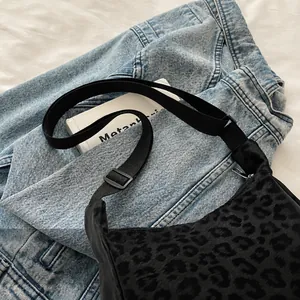 Détail de la bandoulière réglable en nylon noir sur un sac porté croisé léopard