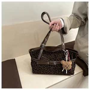Detail der Retro-Leopard-Wildledertasche mit braunem Lederriemen und Plüschbär-Anhänger