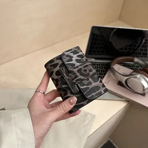 Mini portefeuille carré léopard avec texture cuir et fermoir à boucle tenu à la main