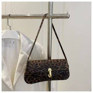 Detail of leopard print handbag with golden pill-shaped buckle on velvet texture