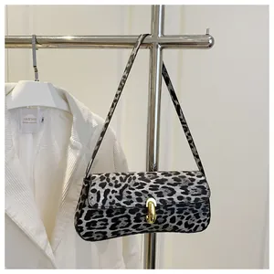 Detailed close-up of leopard print baguette bag with golden metal clasp hanging on a rack
