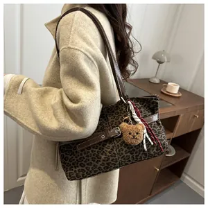 Detail der Vintage-Leoparden-Tragetasche mit dekorativen Riemen und süßem Bärenanhänger