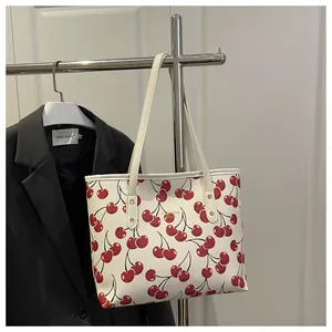 Détail de l'imprimé cerises rouges sur un sac cabas blanc avec lettrage doré