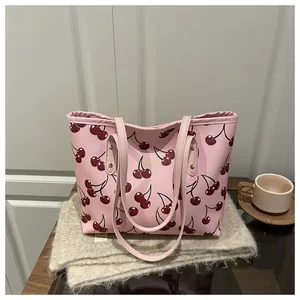 Détail du sac cabas rose avec imprimé cerise, lettrage doré et fines bandoulières élégantes