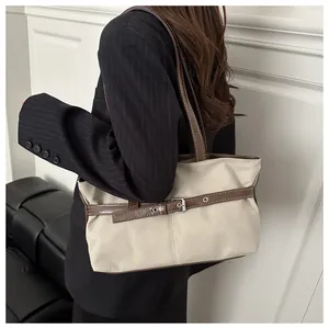 Detail van canvas en bruin lederen draagtas met vintage gesp op een gestreepte blazer
