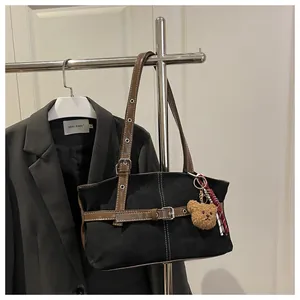 Detail van vintage draagtas met leren riemen en schattige berenbedeltje aan de hanger