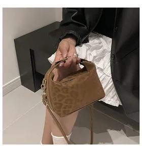 Detail of brown leopard embossed crossbody bag with golden hardware and suede texture