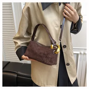 Detail of vintage brown suede baguette bag with a stylish gold chain accent for women