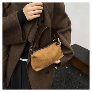 Macro detail of camel suede texture and brown leather stitching on vintage baguette bag