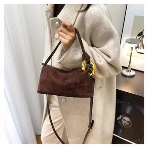 Detail of vintage brown suede baguette bag with large gold metal ring on beige coat