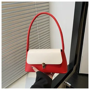 Dettaglio di un’elegante borsa sottobraccio in pelle rossa e bianca con fibbia dorata