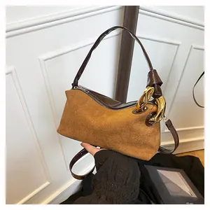 Detail of brown suede baguette bag featuring golden metal chain and dual texture