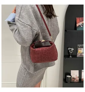 Detail view of burgundy leopard print crescent bag with gold buckle on a light grey outfit