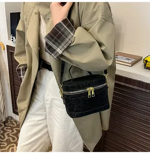 Details der schwarzen Box-Bag mit Leopardenmuster und goldenen Reißverschlüssen am Trenchcoat