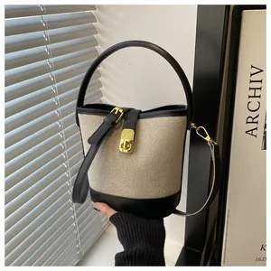 Détail du sac seau en toile avec garniture en cuir noir et fermoir doré élégant