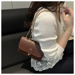Dettaglio borsa a tracolla marrone scuro con catena dorata e chiusura ovale elegante