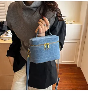Detailansicht einer blauen Zylindertasche mit Leopardenmuster und Goldreißverschluss