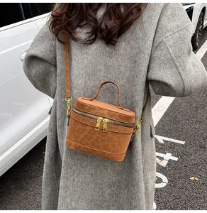 Detail der braunen Box-Tasche mit Tierprägung und Goldreißverschlüssen zum grauen Mantel