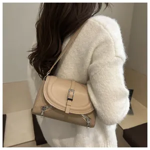 Vue détaillée d'un sac bandoulière beige avec boucle métallique et détails zippés