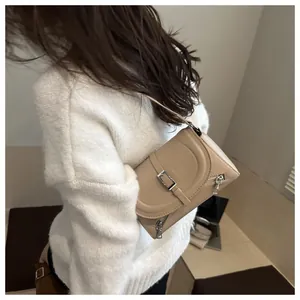 Détail d'un sac bandoulière en cuir beige avec fermeture éclair argentée porté par un mannequin