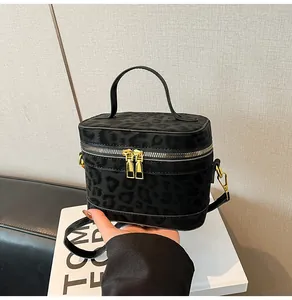 Nahaufnahme der schwarzen Box-Tasche mit Leopardenmuster und goldenen Doppel-Reißverschlüssen