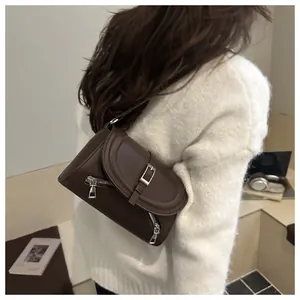 Détail d'un sac à bandoulière en cuir marron foncé avec boucle et fermetures éclair