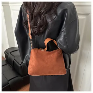 Brown faux suede tote bag with adjustable strap styled on a black leather jacket
