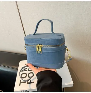 Nahaufnahme der matten blauen Box-Tasche mit goldenen Reißverschlüssen und Riemen