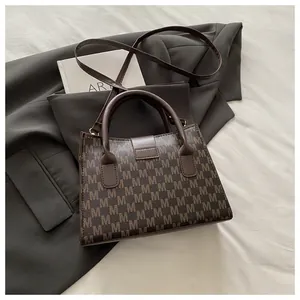 Detail shot of the dark brown monogram tote bag on a professional grey blazer