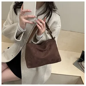 Close-up of matte suede texture and adjustable metal buckle on dark brown handbag