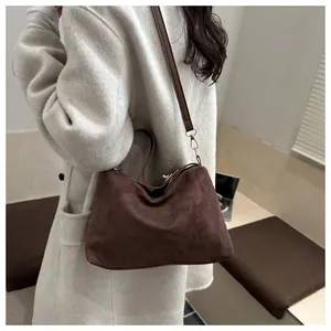 Close-up of a dark brown suede tote bag featuring natural texture and gold hardware