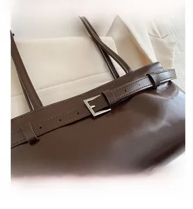 Détail du sac sous les aisselles en cuir ciré marron foncé avec boucle métallique décorative