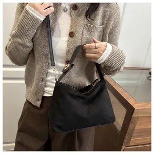 Detail of black matte suede tote bag with golden hardware shown as a crossbody bag on model