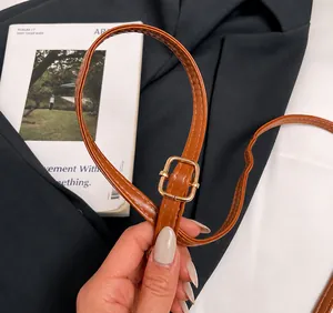 Detailopname van de verstelbare bruine lederen schouderriem met een gouden metalen gesp