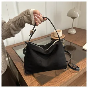 Detail of black suede tote bag showing gold metal zippers and detachable strap hardware