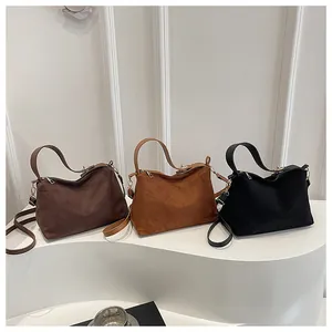 Three matte suede handbags in dark coffee, caramel, and black colors on display stands