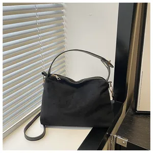 Detail of black suede tote bag with golden zipper and adjustable shoulder strap