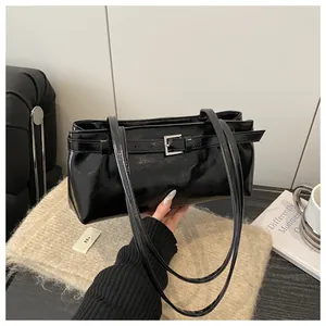 Détail du sac à bandoulière en cuir huilé noir brillant avec boucle de décoration