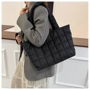 Close-up of black quilted tote bag with padded shoulder straps and square stitching