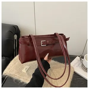 Détail d'un sac sous les aisselles en cuir ciré bordeaux avec une boucle métallique chic