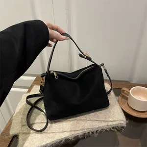 Retro black faux suede tote bag with golden hardware and adjustable strap on cozy background