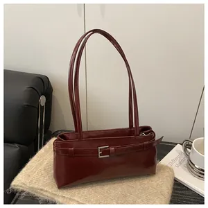 Vue détaillée du sac baguette bordeaux avec boucle argentée sur un tapis texturé beige